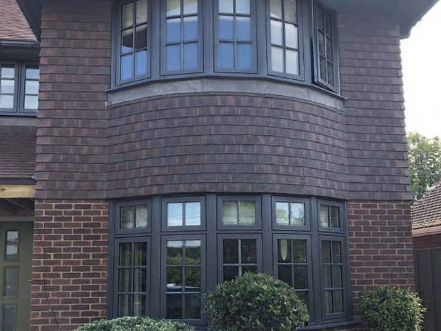 Anthracite bay windows on a brick house