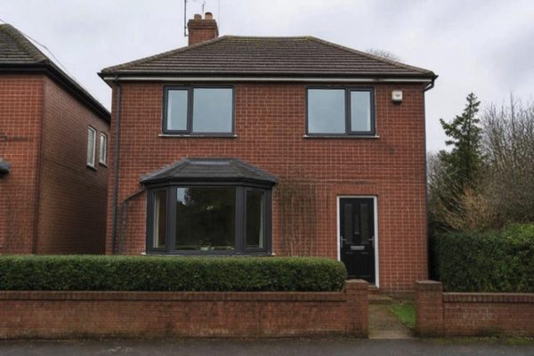 AI visualisation: the same house with anthracite uPVC casement windows, including the bay