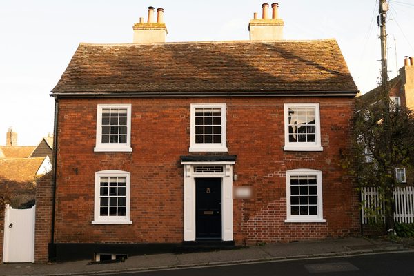 Photograph: a red-brick house with white sash-style windows