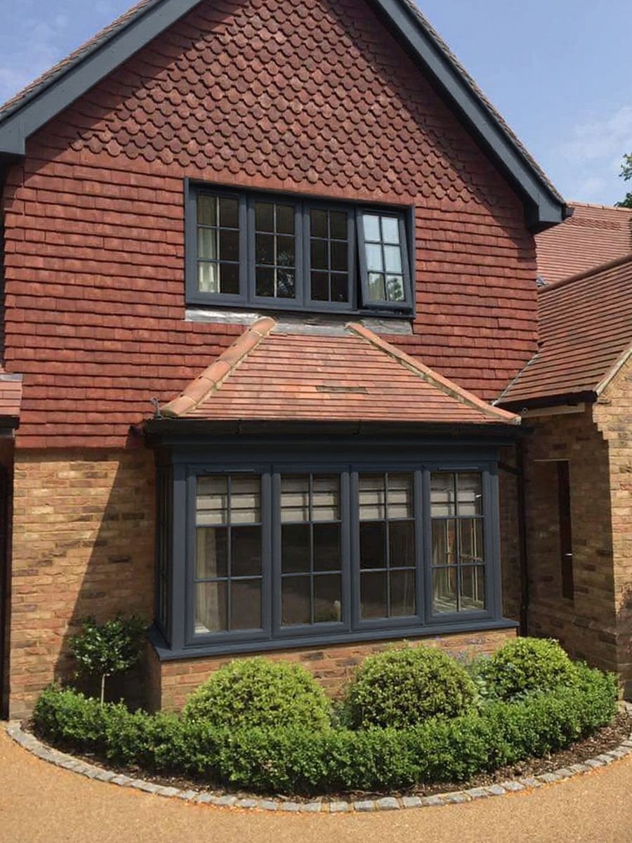 A tile-hung detached home after its frames were recoloured slate grey