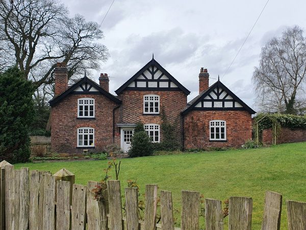Photograph: a red-brick house with black and white gables and white windows with glazing bars